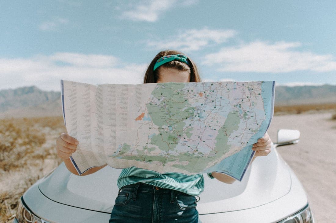 A person checking a route map beside a loaded car