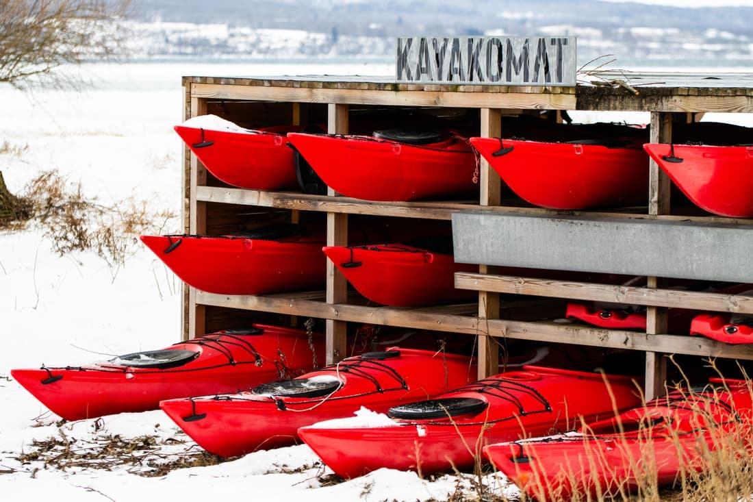 Kayaks strapped to a vehicle's roof rack beside a lake