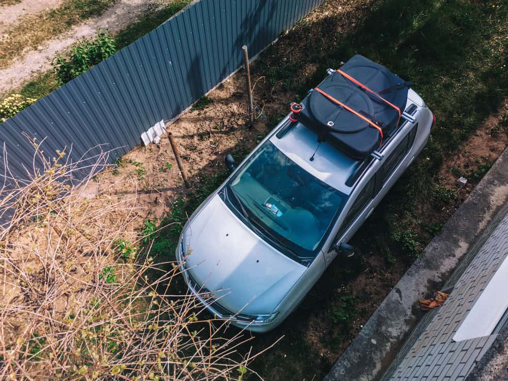 A soft waterproof cargo bag strapped to the roof of a car