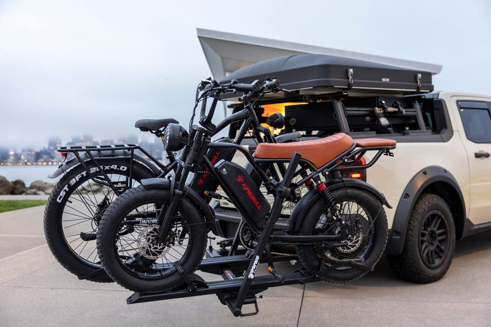 An electric bicycle standing beside a car with a rear rack fitted