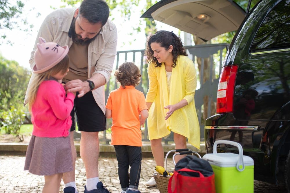 A family loading bags into a car before a trip