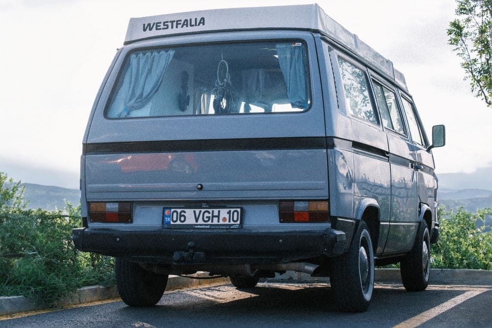 A motorhome parked at a campsite with a rear-mounted cargo carrier