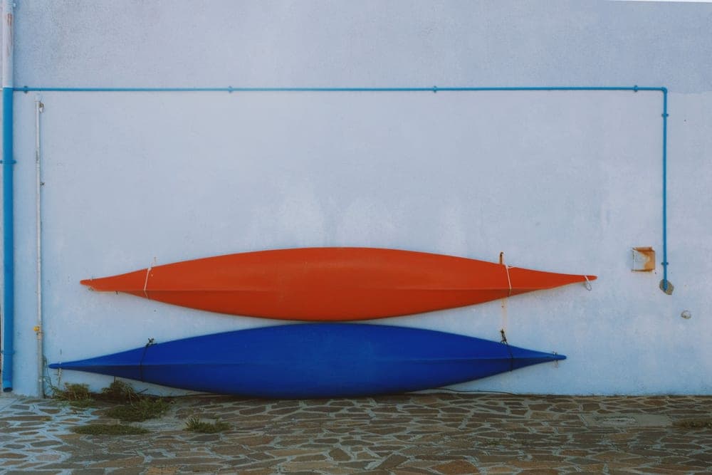 Kayaks secured to the roof of a car beside water