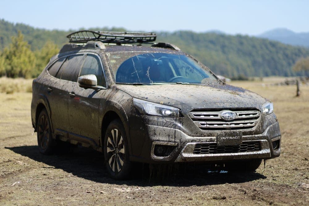 A raised estate wagon parked on a gravel pull-off with roof rails